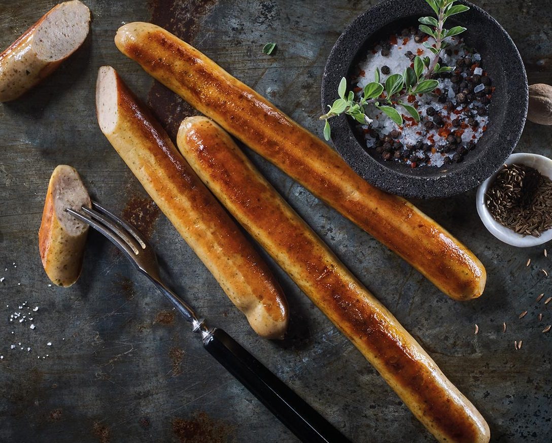 Prämierte Wurstwaren Verschiedene Wurstsorten in roten Körben, einige mariniert, andere unverpackt.